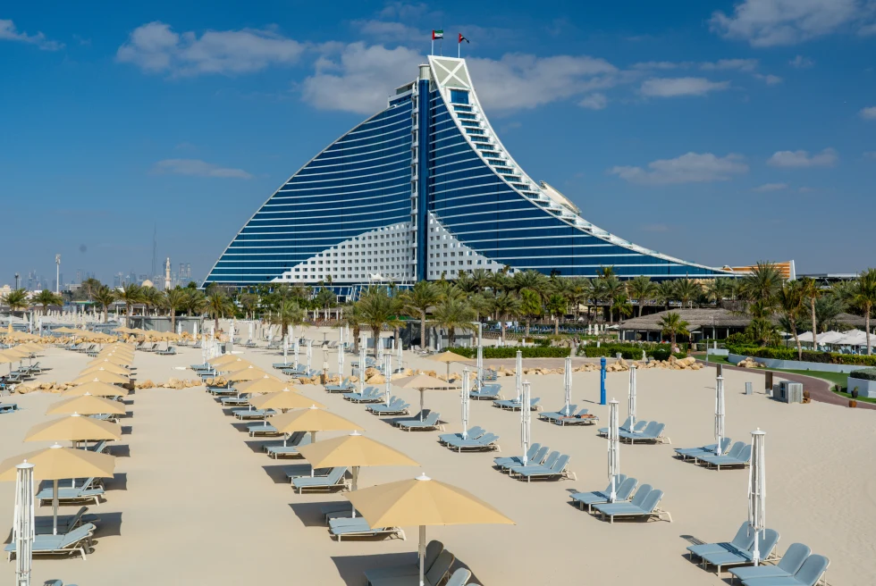 Chairs and umbrellas at Jumeirah Beach in Dubai with building in background