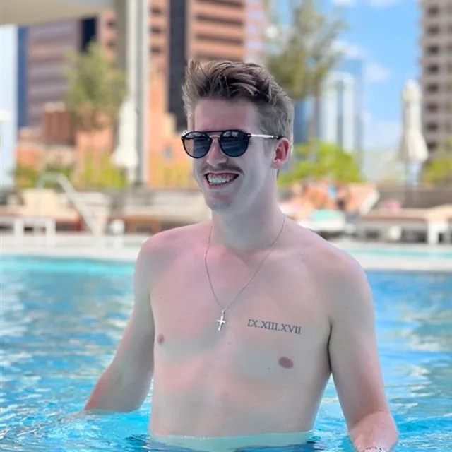 Travel advisor Dylan Raymond wades in a hotel pool wearing sunglasses