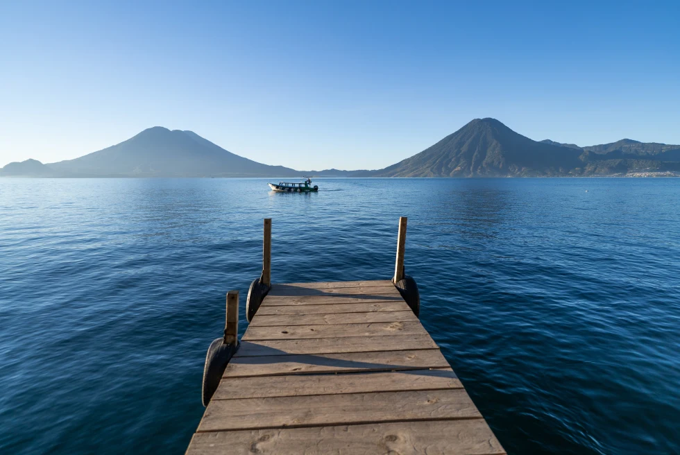 lake with a boat and mountains in the distance in the morning