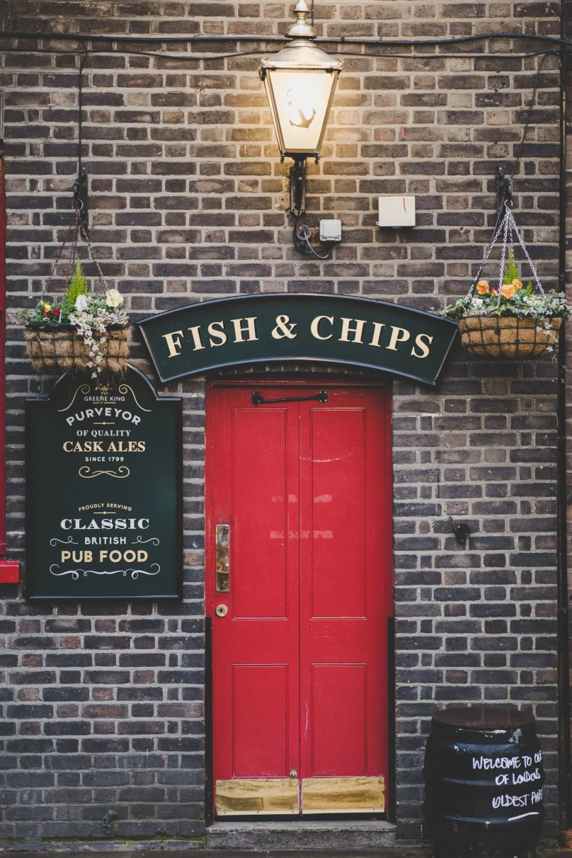 entrance to a pub with a red door and a sign that reads, "Fish & Chips."