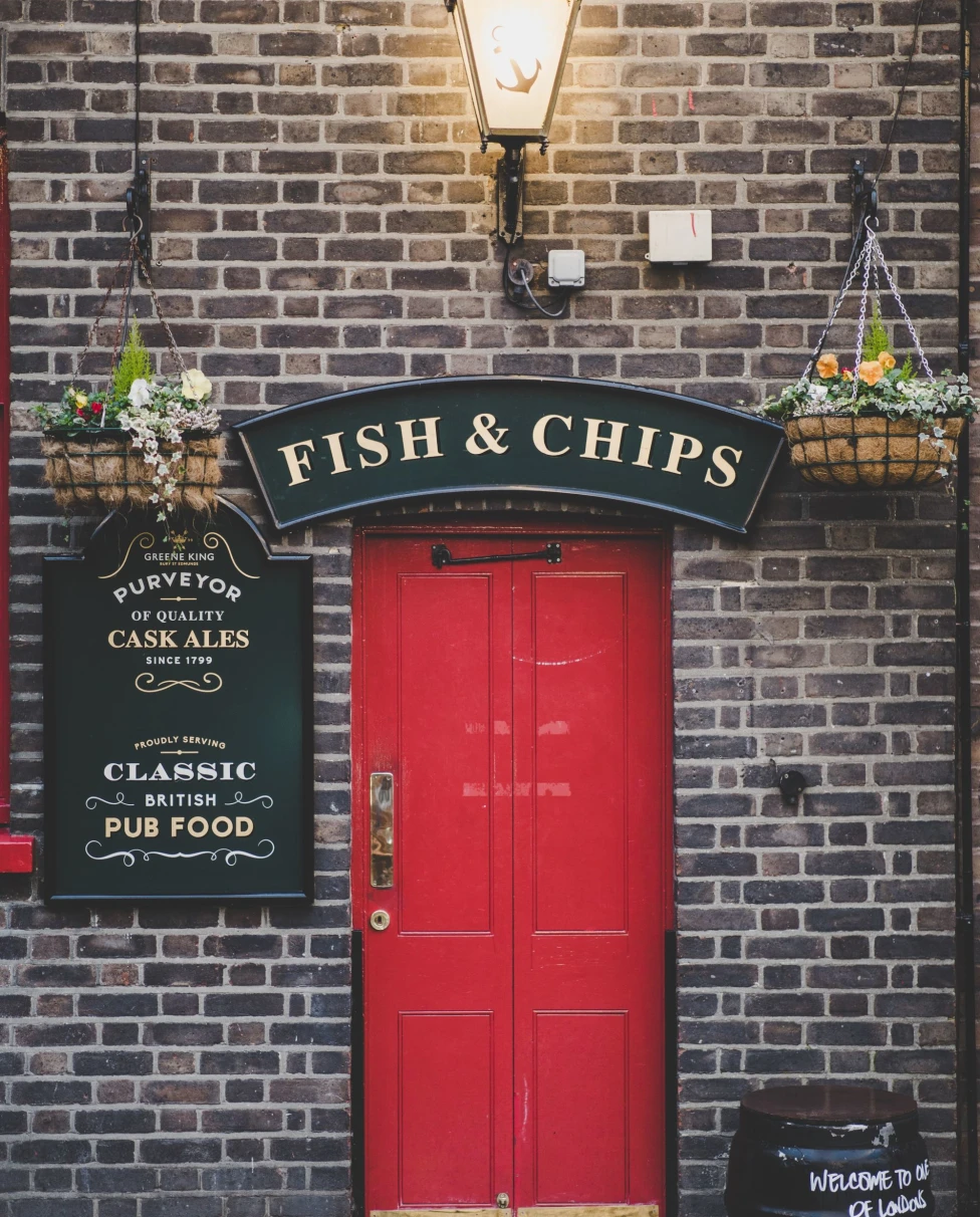 entrance to a pub with a red door and a sign that reads, "Fish & Chips."