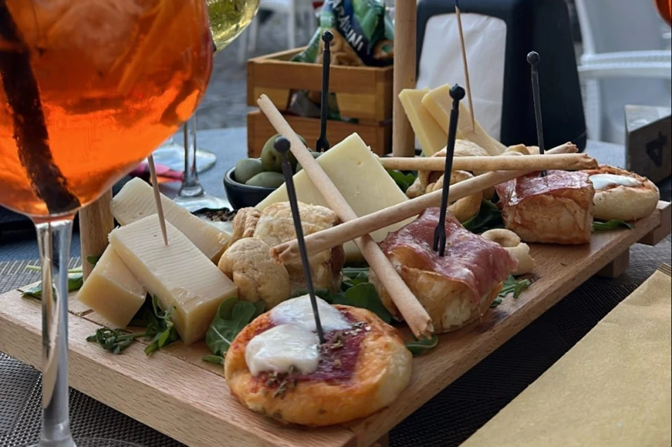 A cheese and bread board with an orange drink. 
