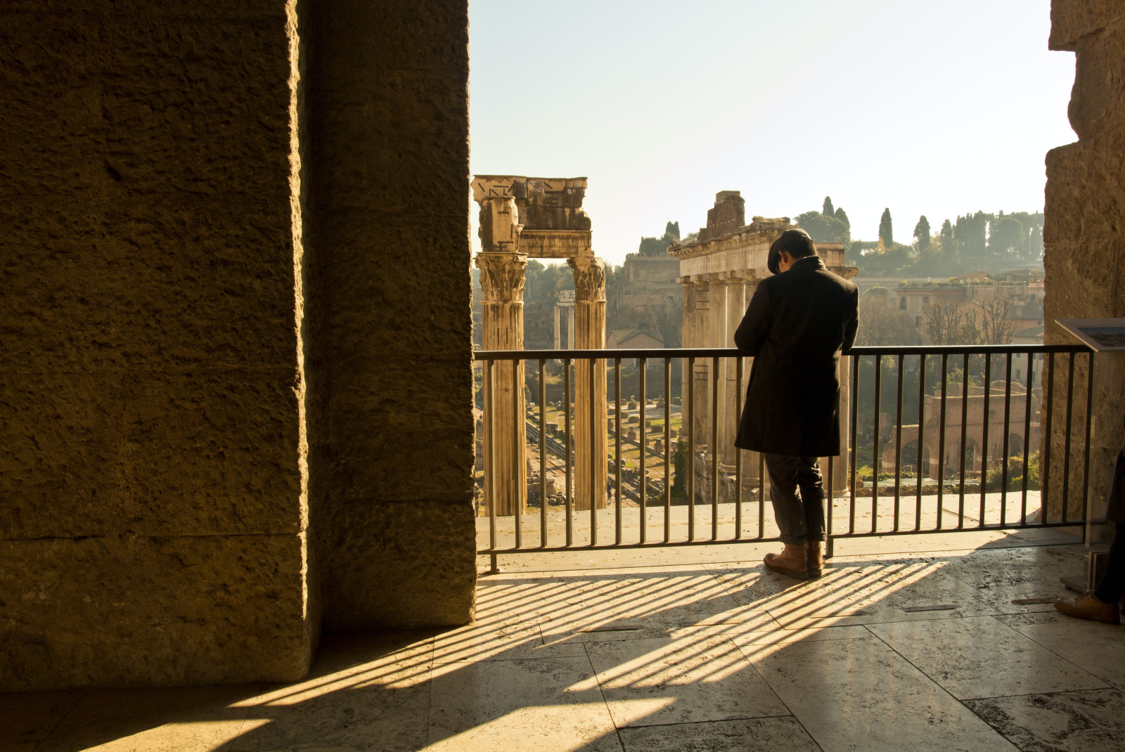 man standing on balcony overlooking ancient structures