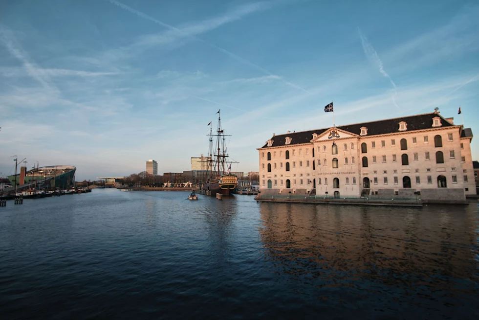 a museum on the water with a large historic sailboat