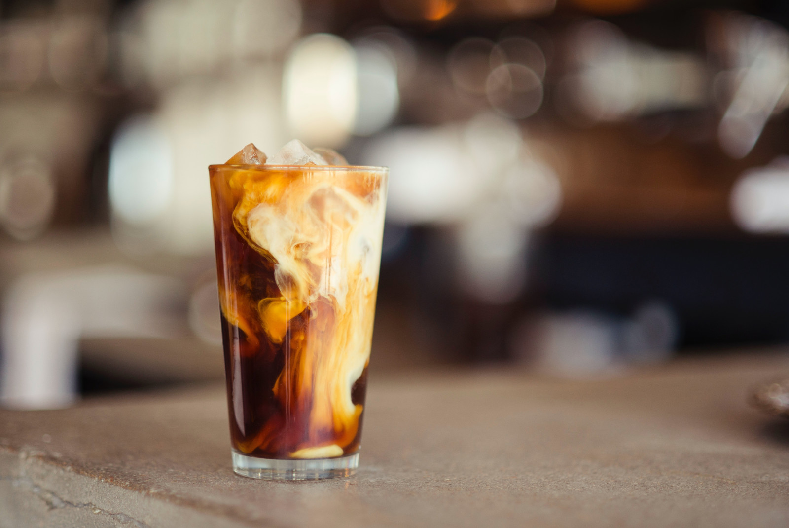 Glass with iced coffee and milk on wooden table