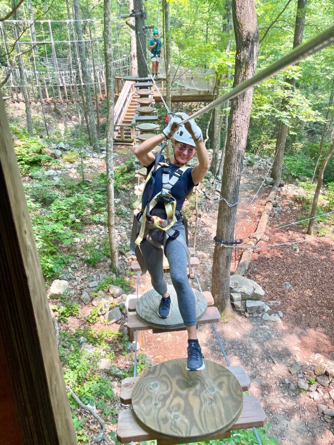 A person zip-lining through the forest with gear and ropes tied to them. 