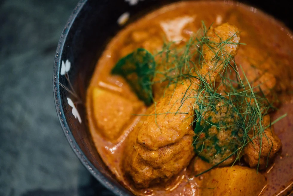 Chicken curry in black bowl.