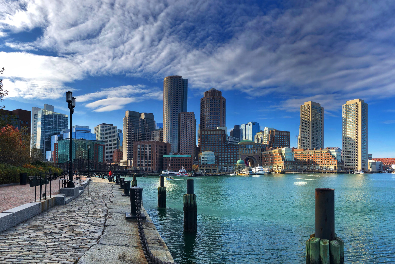 Path next to body of water with buildings in the background during daytime