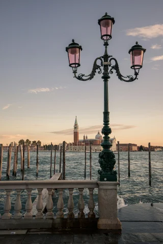 A lamp post at the edge of the water in Venice at sunset.