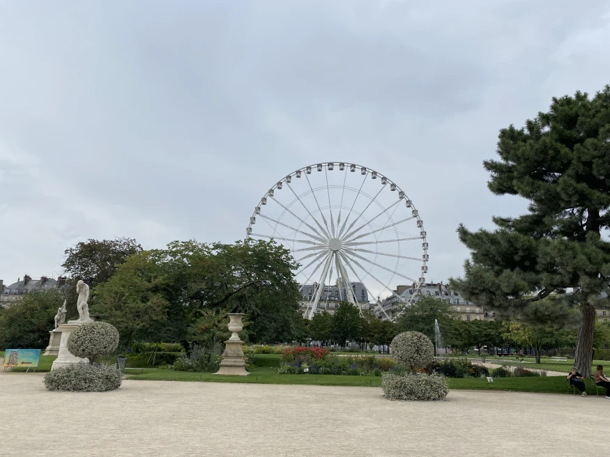 ferris wheel next to gardens with cloudy skies