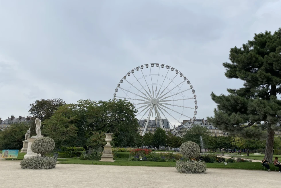 ferris wheel next to gardens with cloudy skies