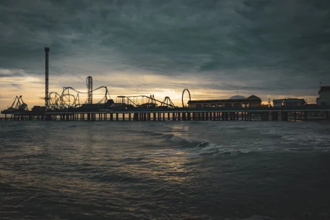 a pier with roller coasters at night
