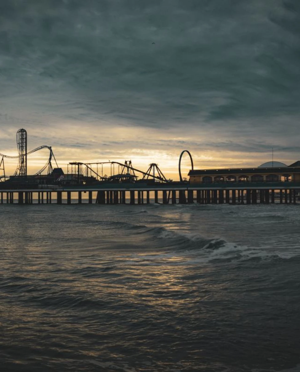 a pier with roller coasters at night