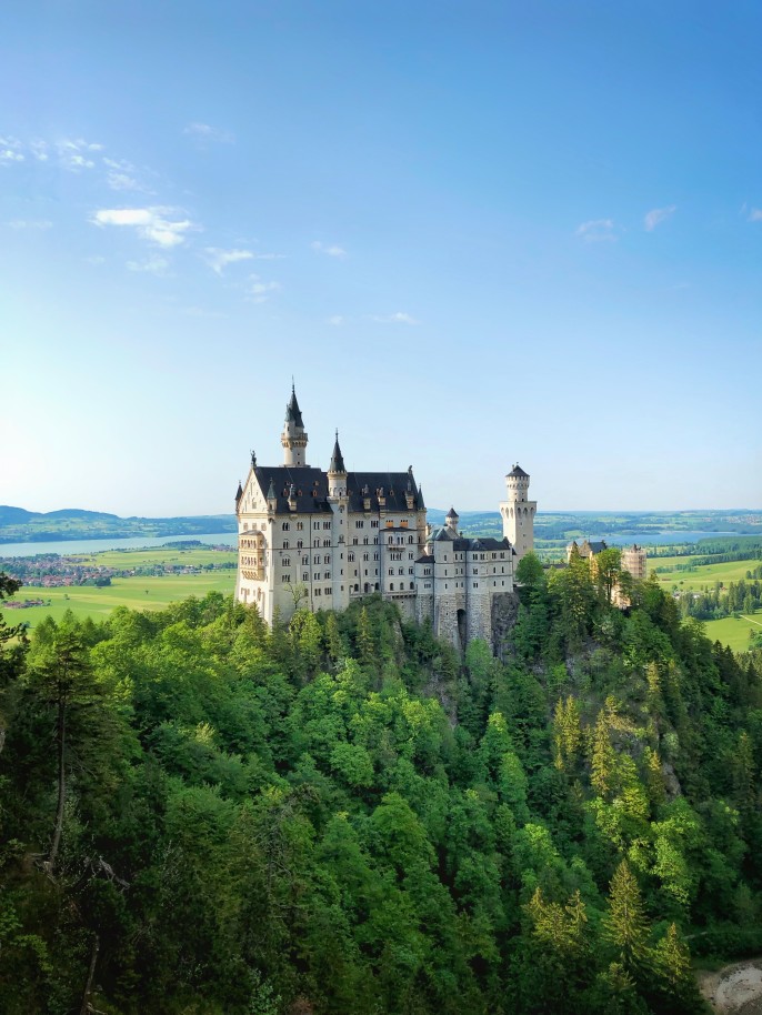 Neuschwanstein Castle surrounded by trees with blue skies in Bavaria