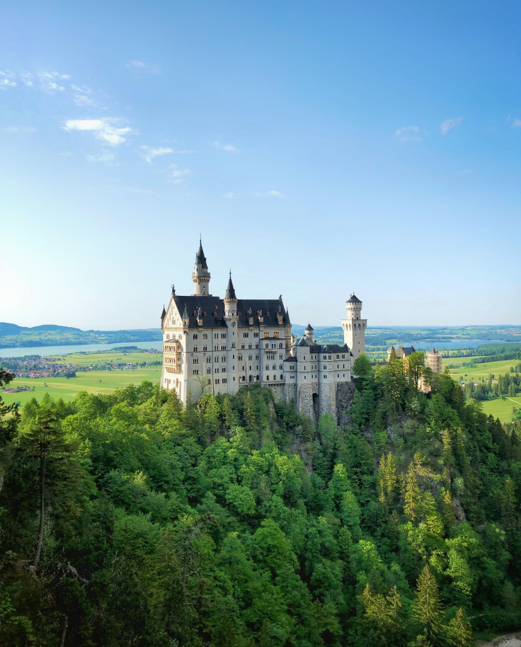 Neuschwanstein Castle surrounded by trees with blue skies in Bavaria