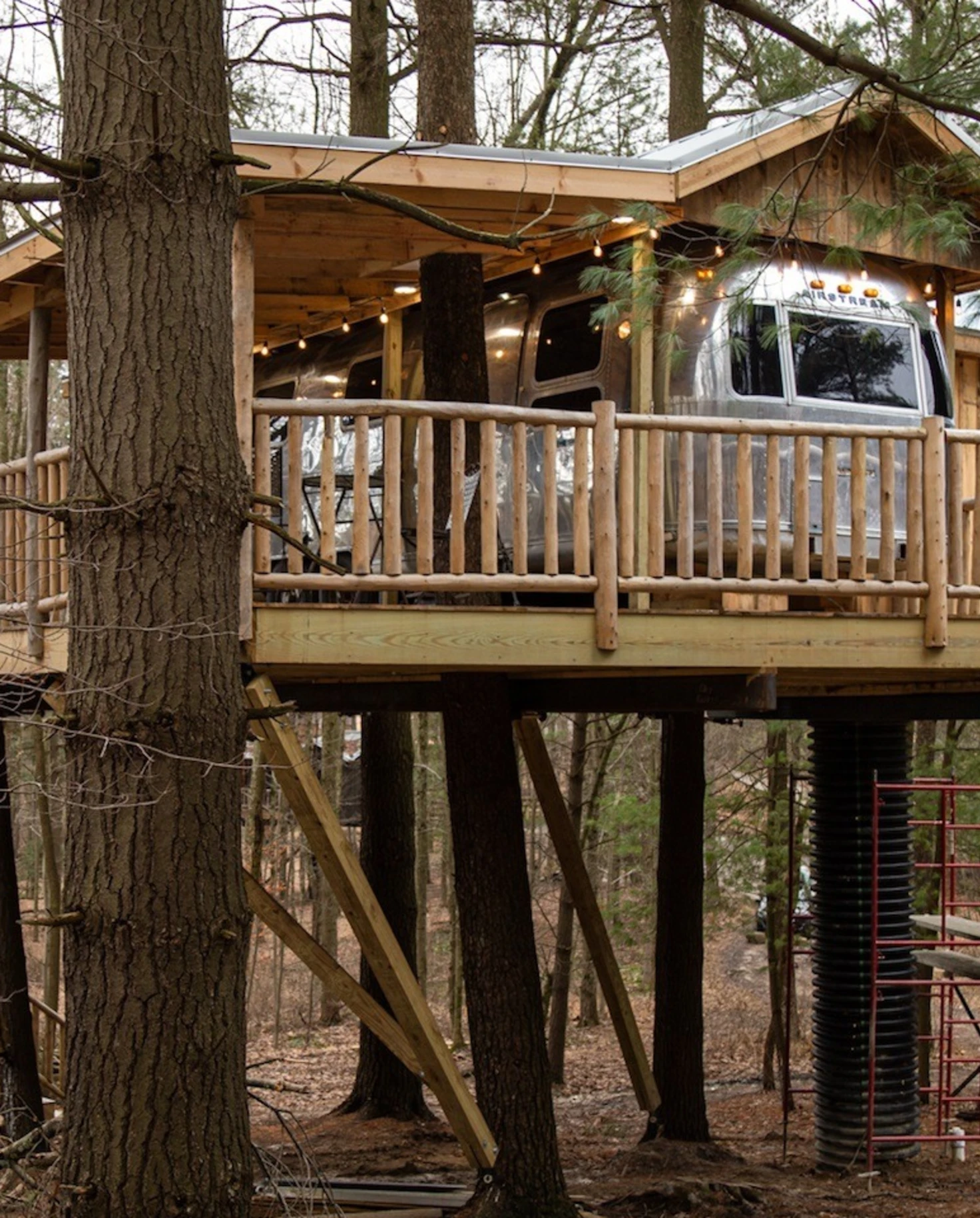 A treehouse in a forest with RV parked in it.