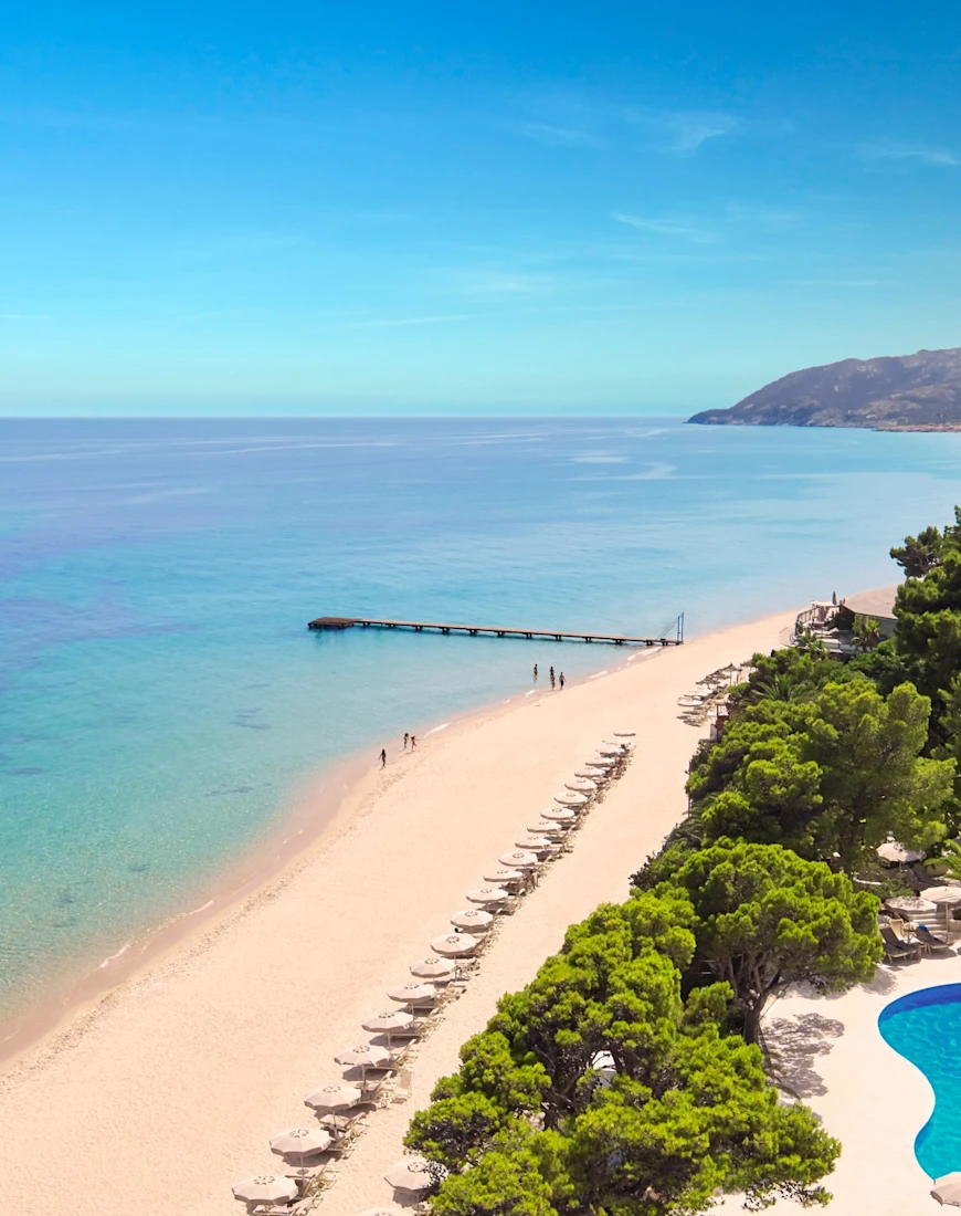 aerial view of a sandy beach dotted with beige umbrellas