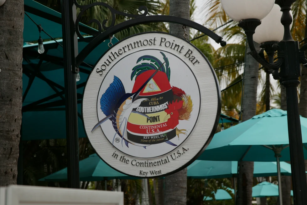 White sign hanging with trees in background during daytime