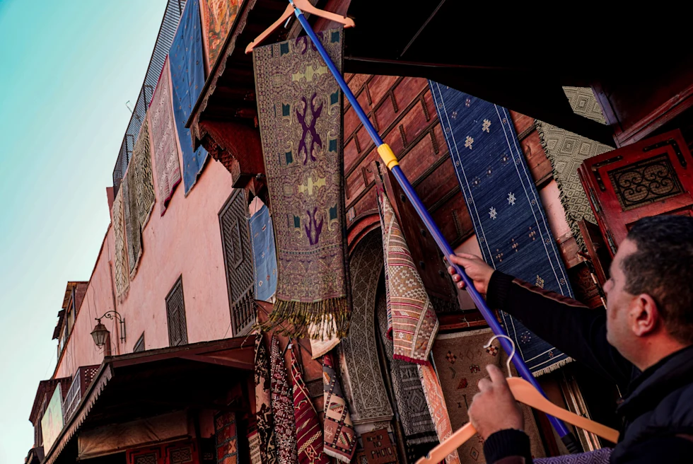 A vendor pointing out textiles at a medina in Morocco.