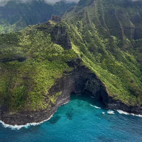 aerial view of green mountain next to body of water