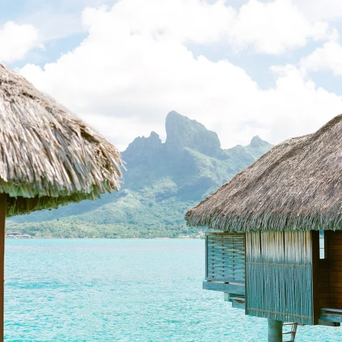 Hut on body of water with mountain in background during daytime