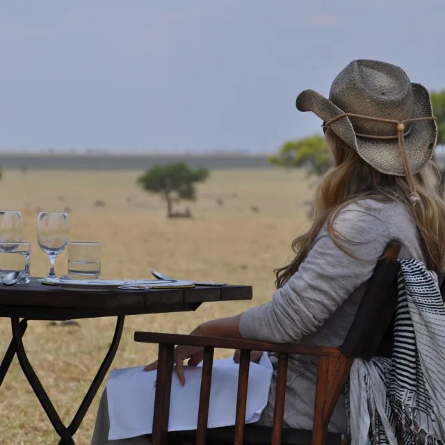 Travel advisor Jennifer Seelicke in a cowboy hat sitting at a table overlooking a meadow