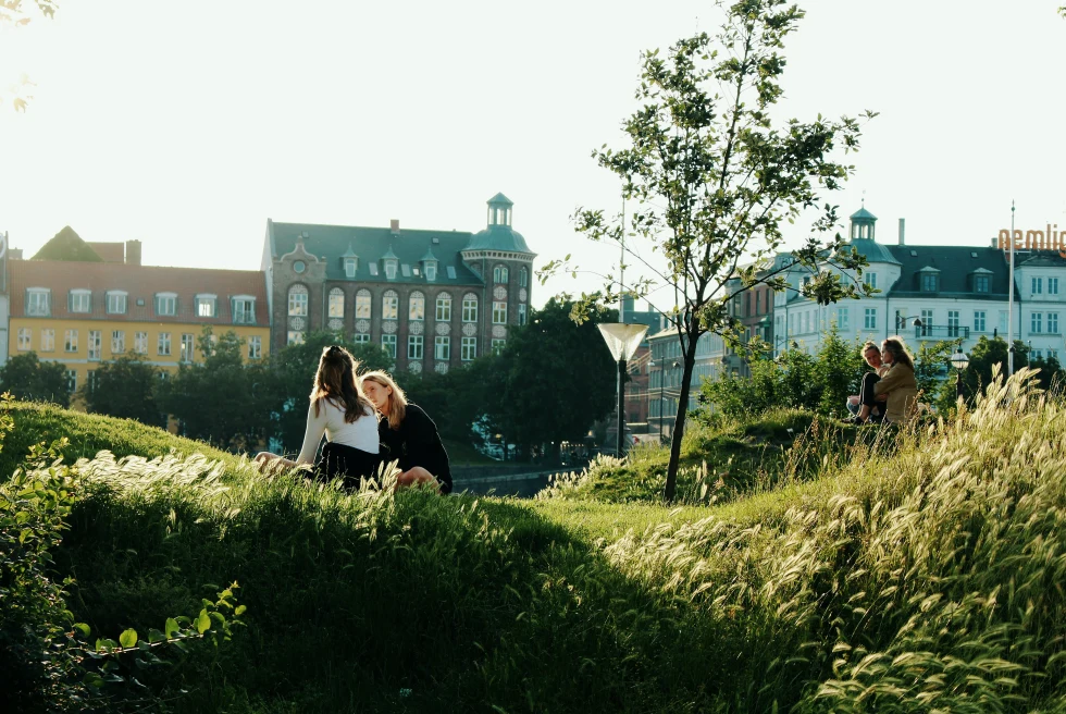 2 Girls sitting on the grass in front of a huge building