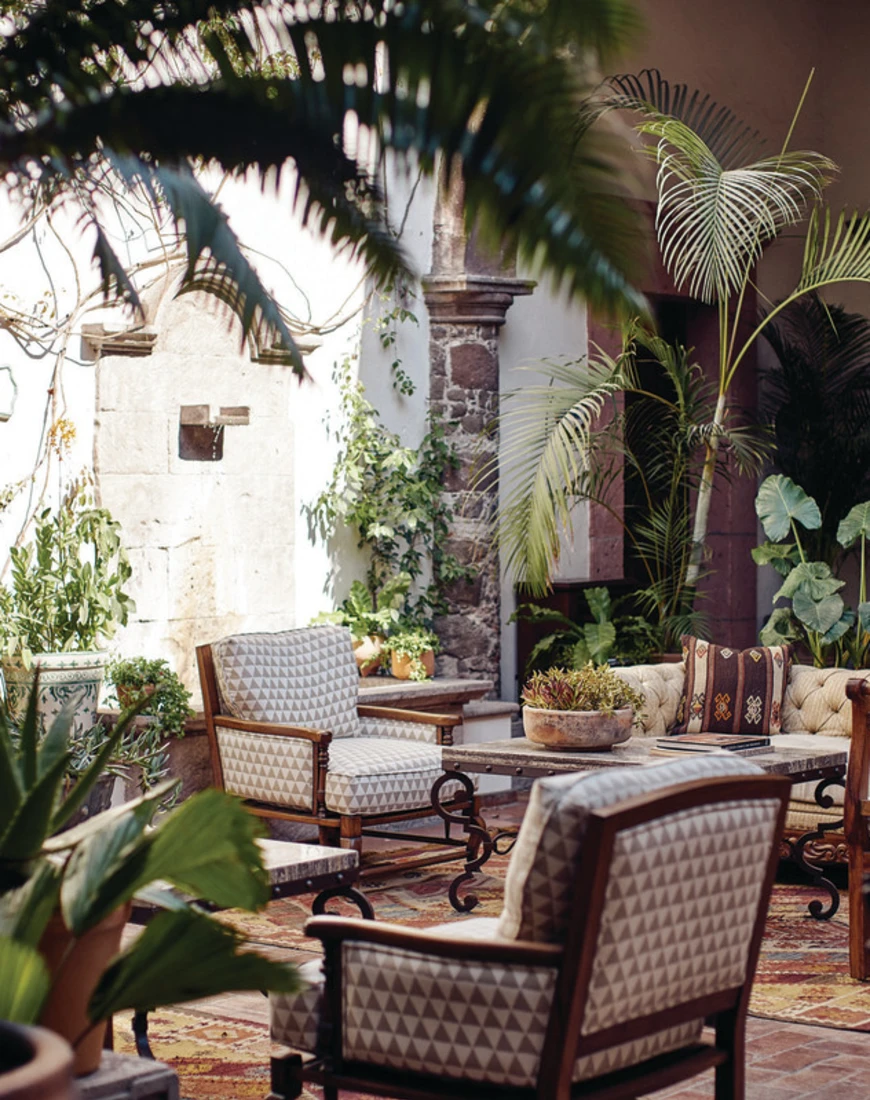 plush tables and chairs in an outdoor seating area filled with palm trees