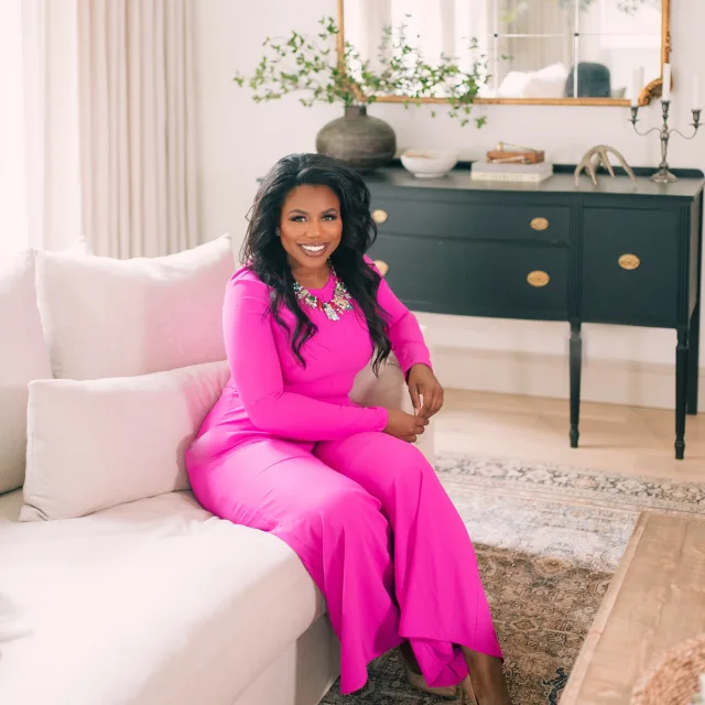 Travel Advisor Aubrey Jackson sitting on a sofa in a candy pink dress. 