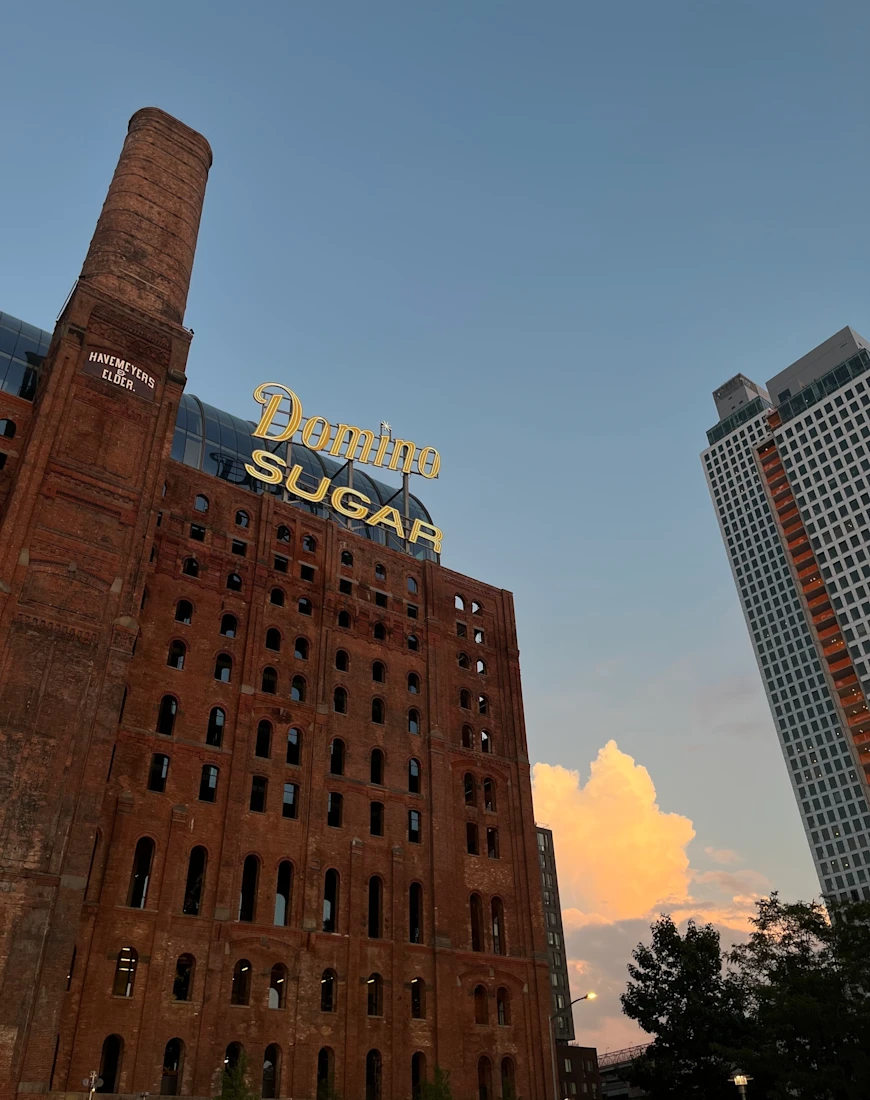a brick building with a lit sign that reads "Domino Sugar."