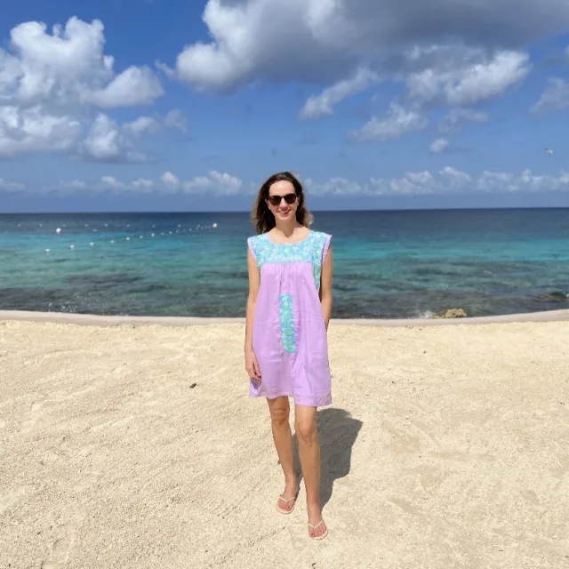 woman in a pink and blue dress standing on a sunny beach