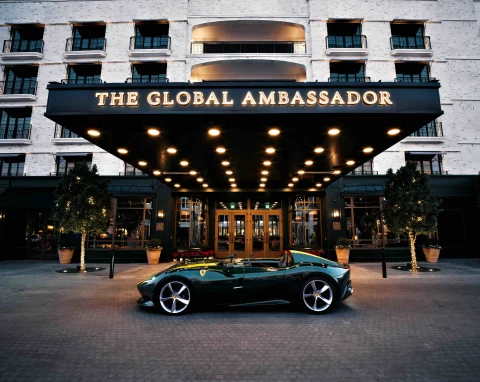 The entrance to the Global Ambassador, with a large black porte-cochère with gold lettering and a black sports car parked out front.