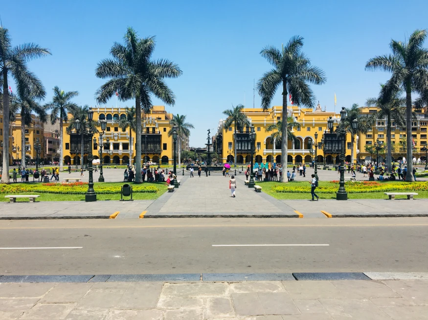 A yellow building with tall green palm trees in Lima, Peru.