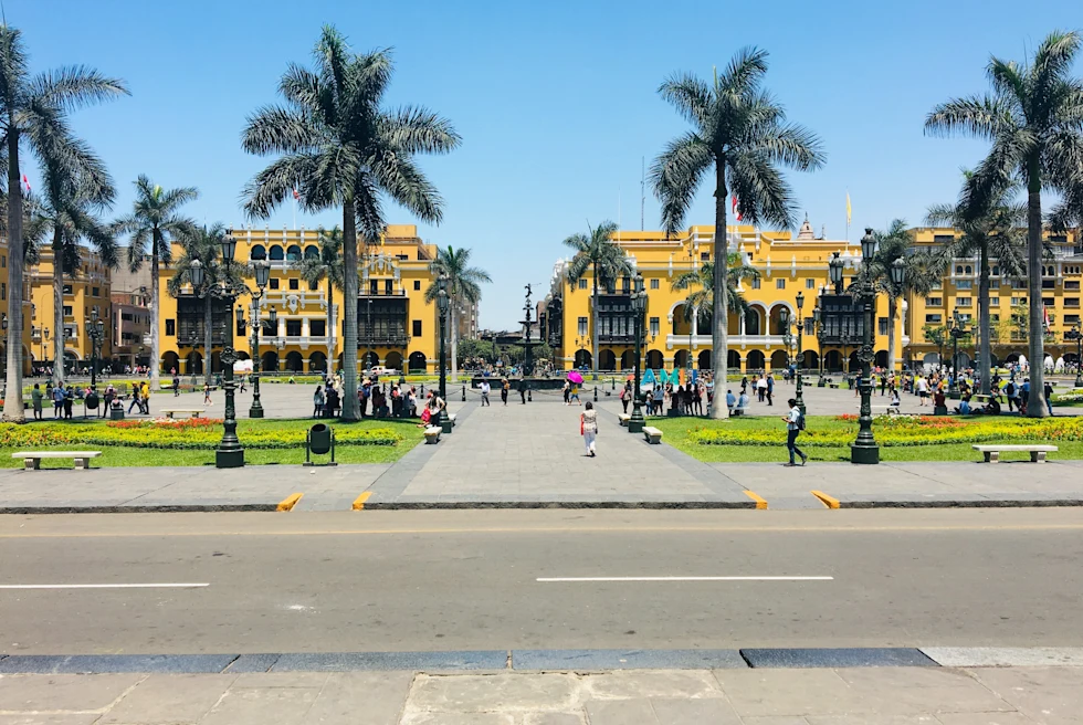 A yellow building with tall green palm trees in Lima, Peru.