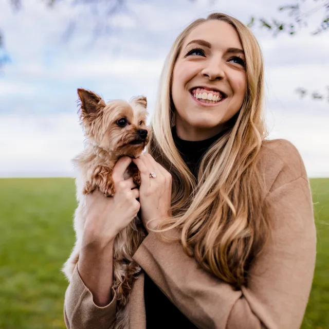 Courtney posing with her dog in a field during the daytime.