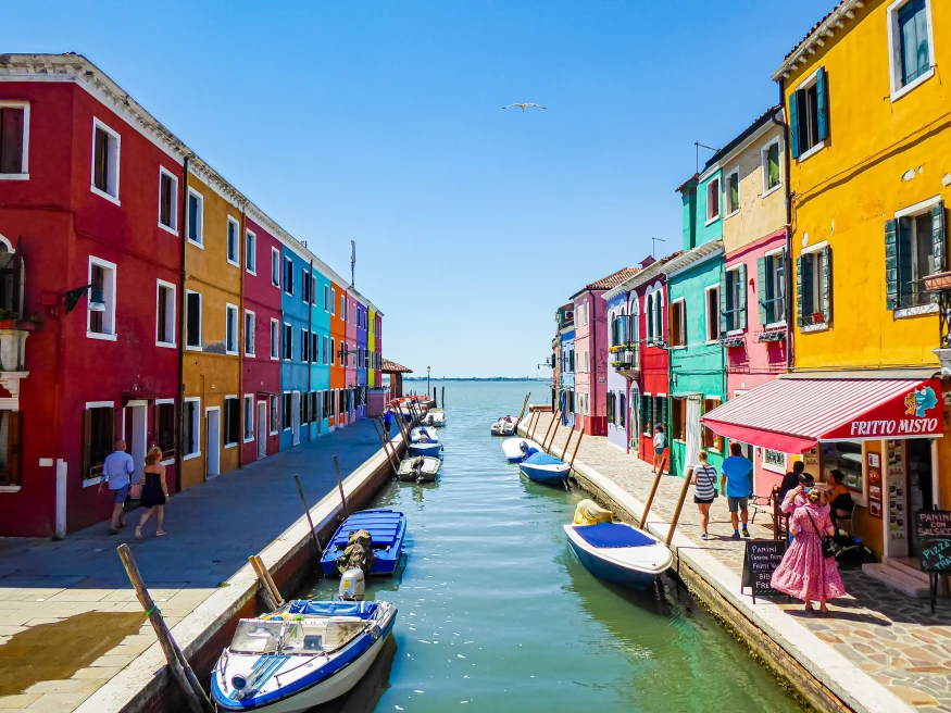 burano venice italy yellow teal pink red buildings canal with white boats