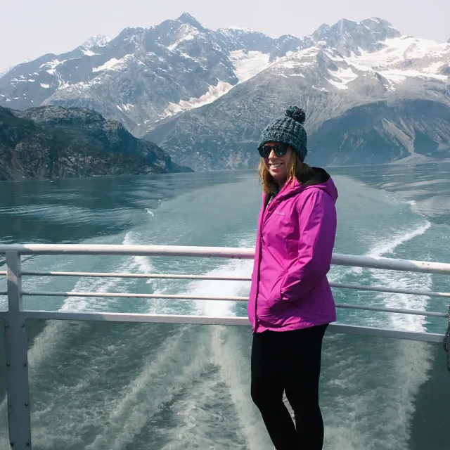 Travel Advisor Erin Spilman in a pink jacket in front of a glacier. 