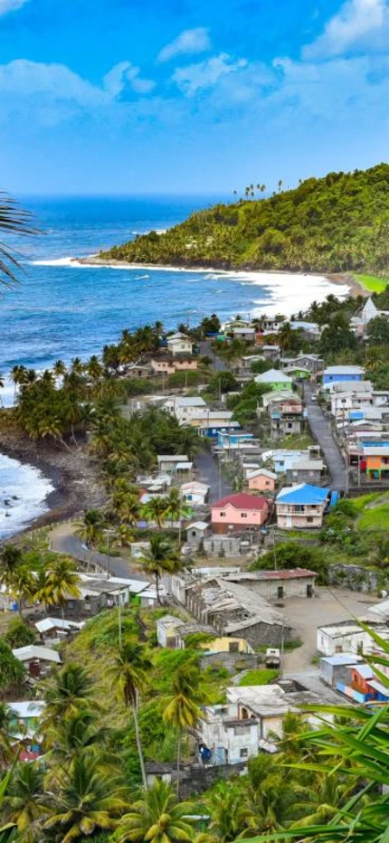 Small village along the ocean surrounded by green hills on a sunny day in St. Vincent