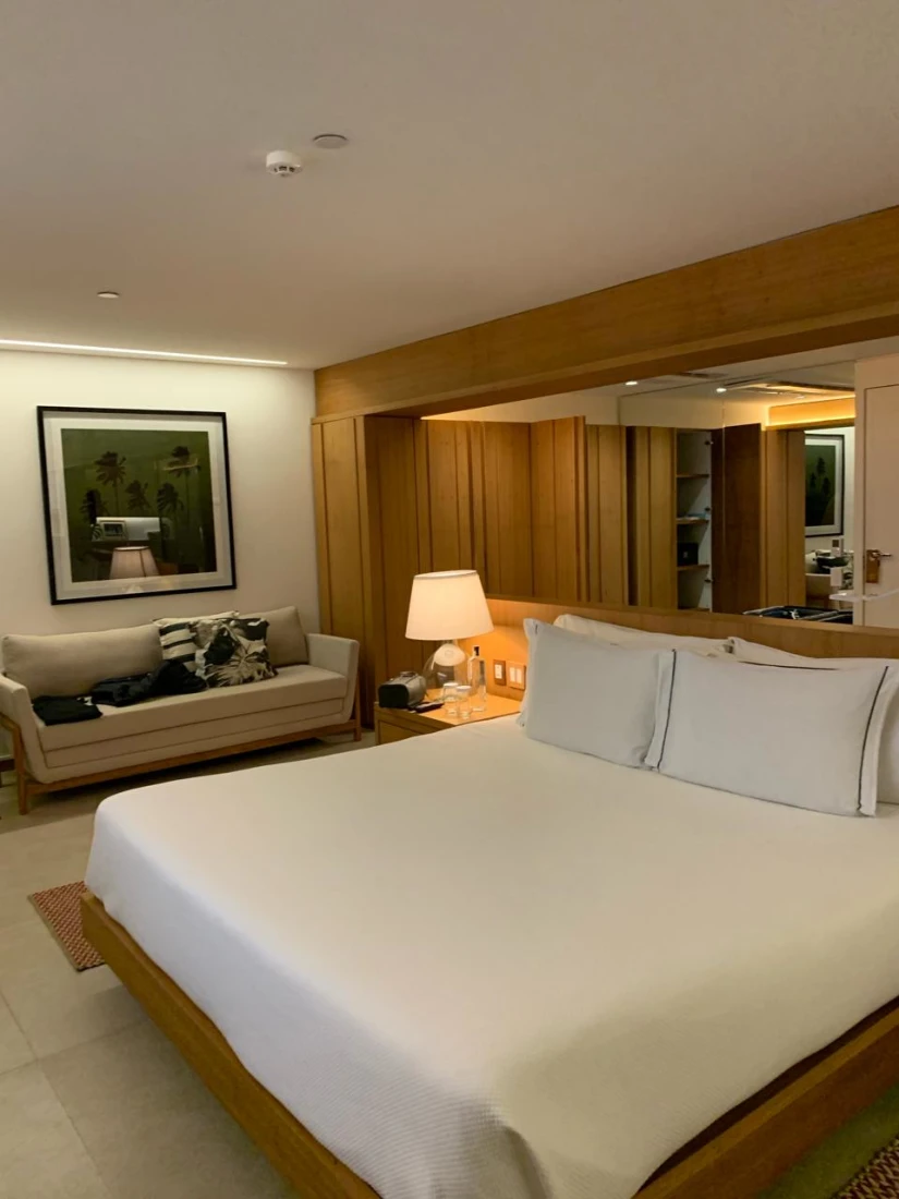 Modern hotel bedroom interior with large bed with white bedding and wooden features