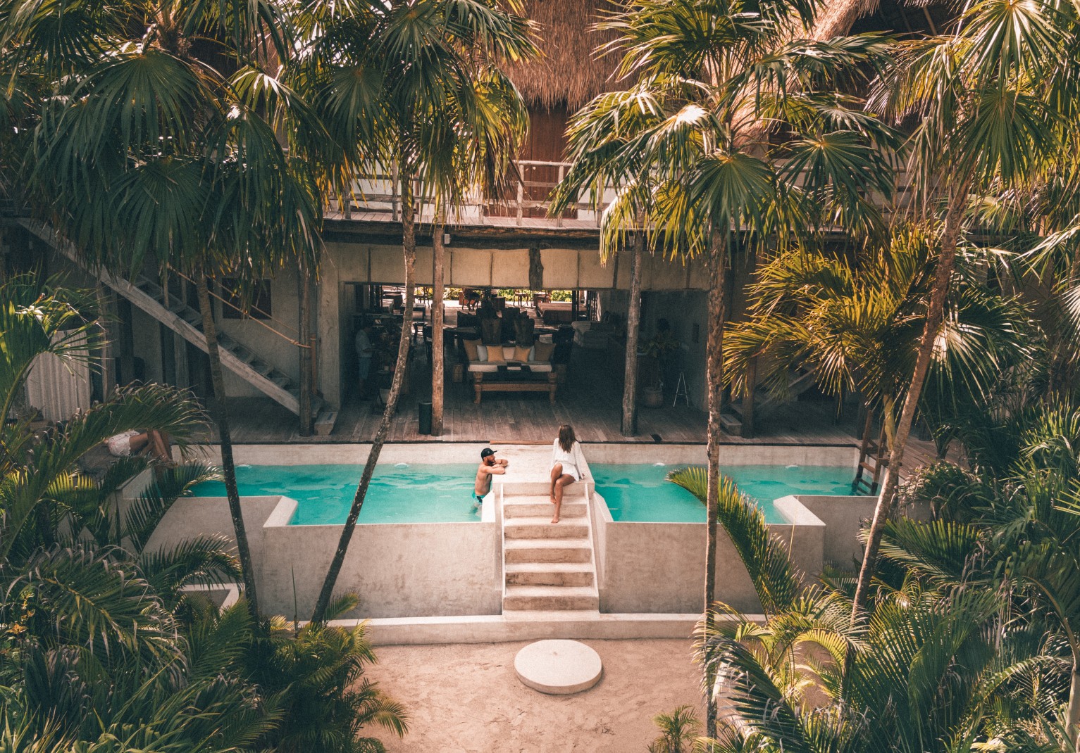Hotel pool in Tulum, Mexico surrounded by palm trees