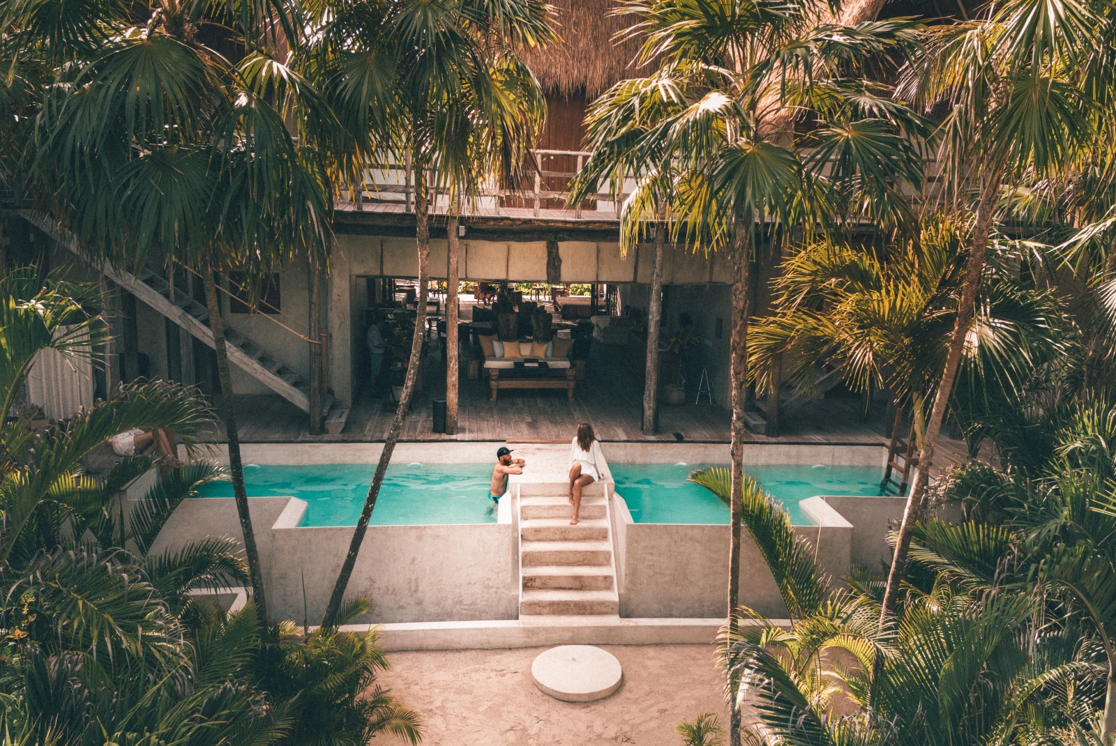 Hotel pool in Tulum, Mexico surrounded by palm trees