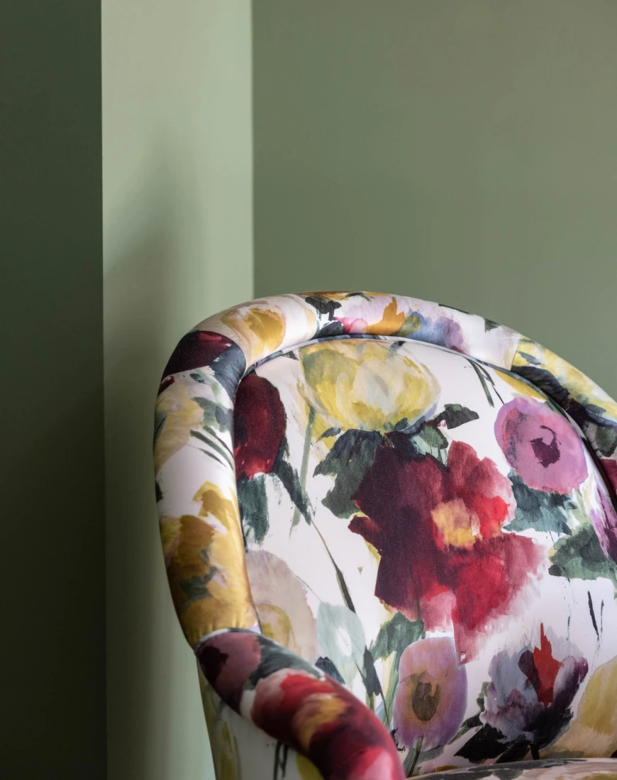 a floral-patterned upholstered chair in front of a green wall