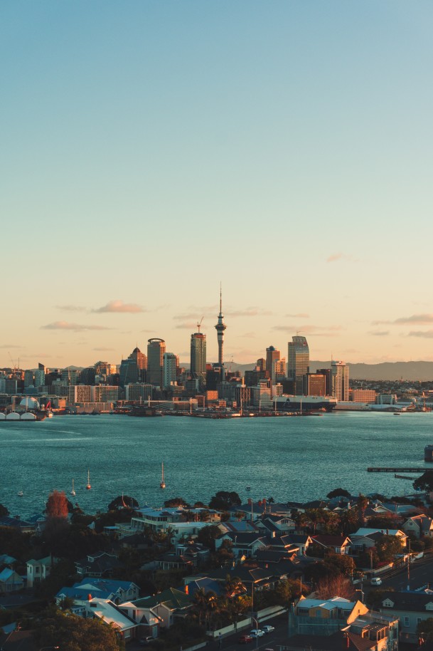 A city view of Auckland, New Zealand at sunset overlooking a blue lake.