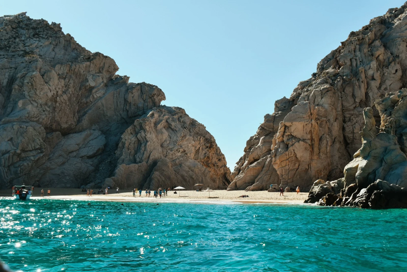 beach with sparkling turquoise waters and stone formations on the sand