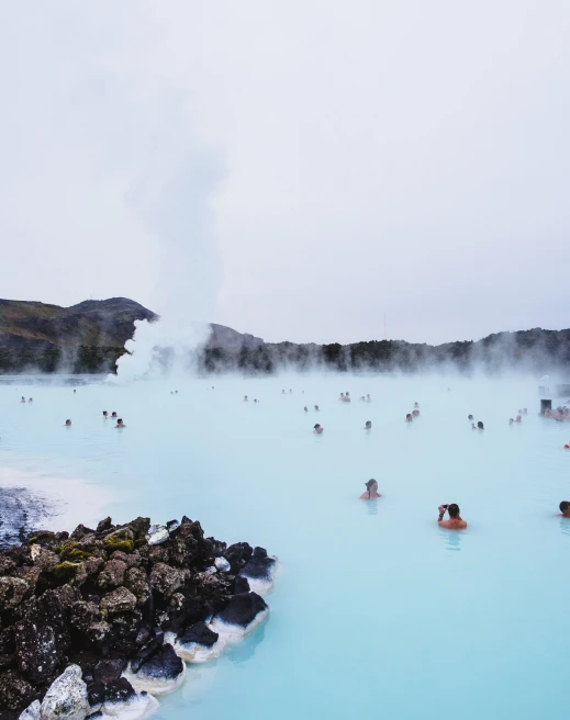 Tourists swim in blue lagoon in Iceland on a cloudy day
