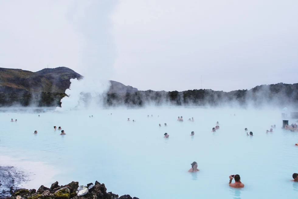 Tourists swim in blue lagoon in Iceland on a cloudy day