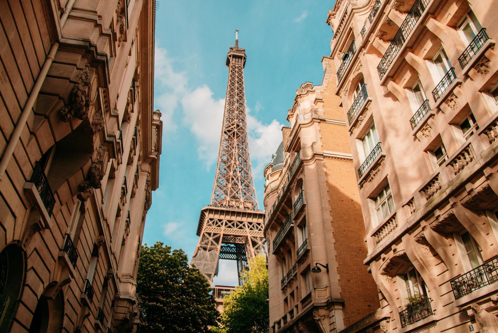 Eiffel Tower peeking through narrow street in Paris.