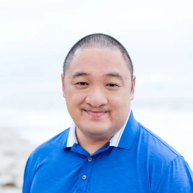 Travel Advisor Nathan Roemer in a blue shirt in front of the beach.