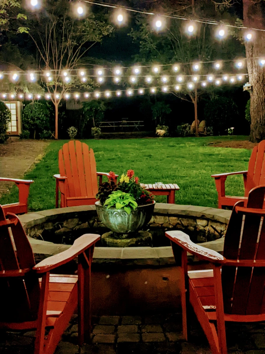 chairs around a fire pit with string lights