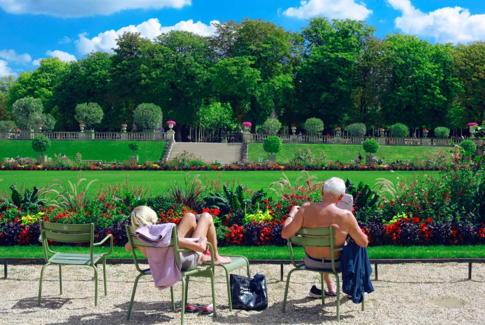 A couple sunbathing on the benches in the Luxembourg Gardens.
